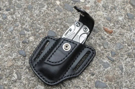 Artistic view of a Leatherman Charge multitool sheath shown in black leather with a nickel snap