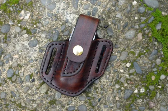 Front view of a Leatherman Charge multitool sheath shown in chocolate brown leather with a brass snap