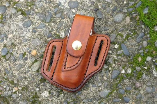 Front view of a Leatherman Charge multitool sheath shown in cognac brown leather with a brass snap