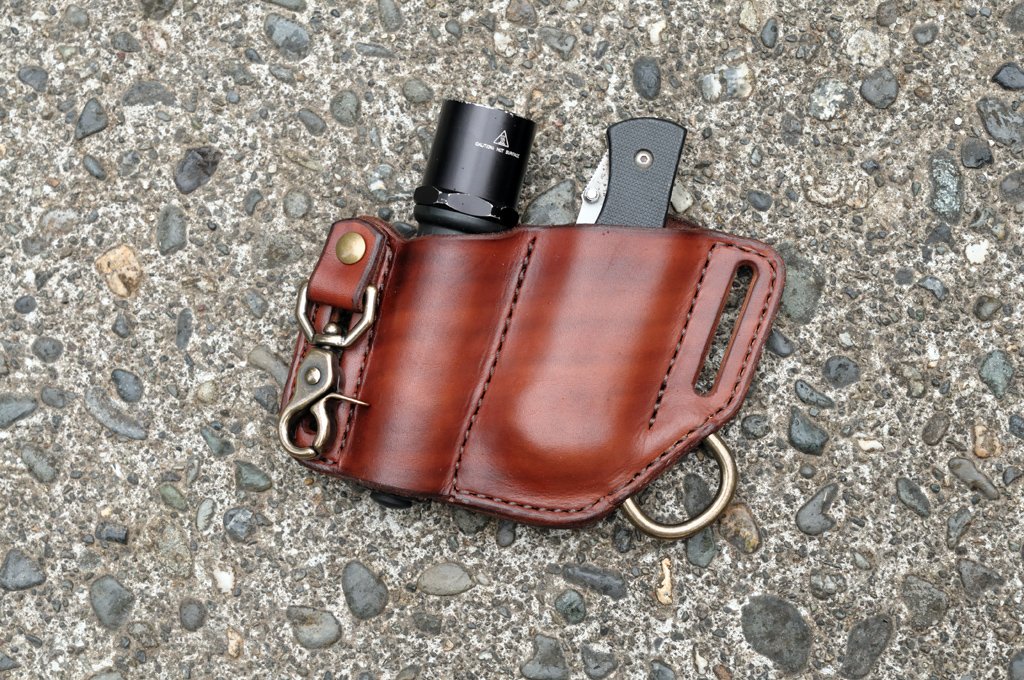 Front view of a custom folding knife and flashlight combo holster in mahogany leather with keychain clip.