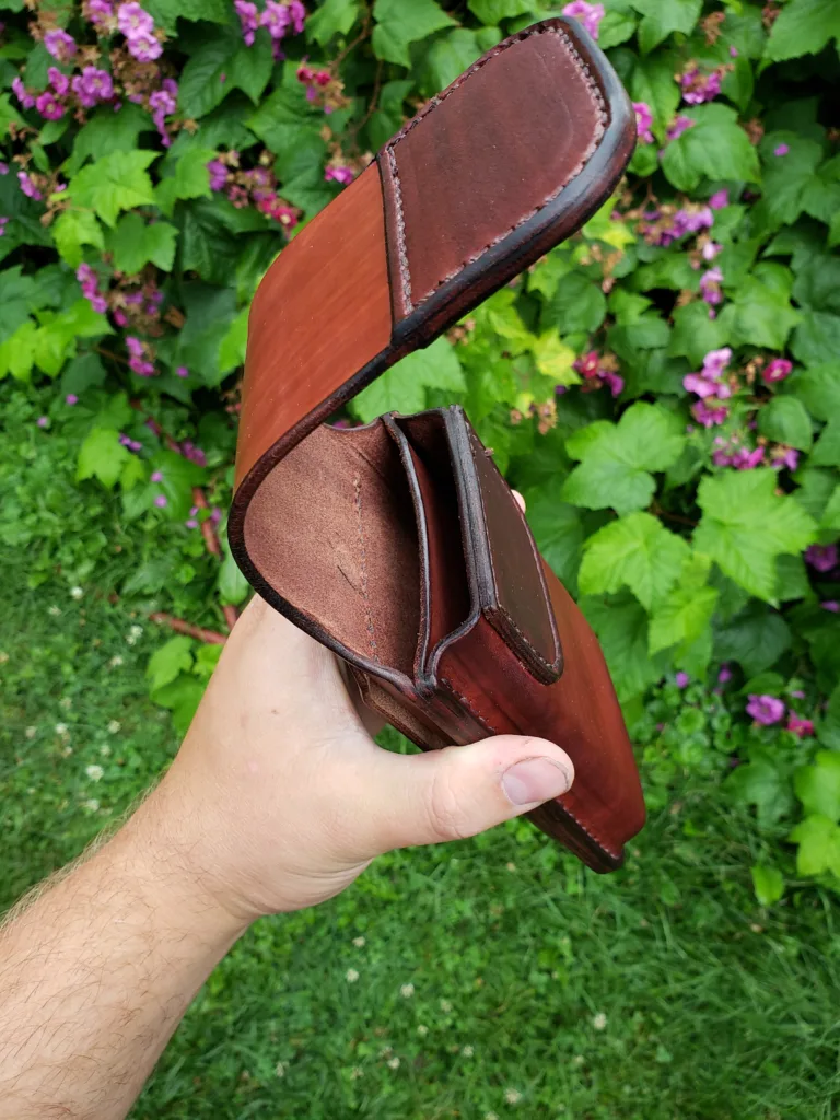 Angled view down the top of a holster made from mahogany leather to fit two phones with a magnetic flap closure over the top.
