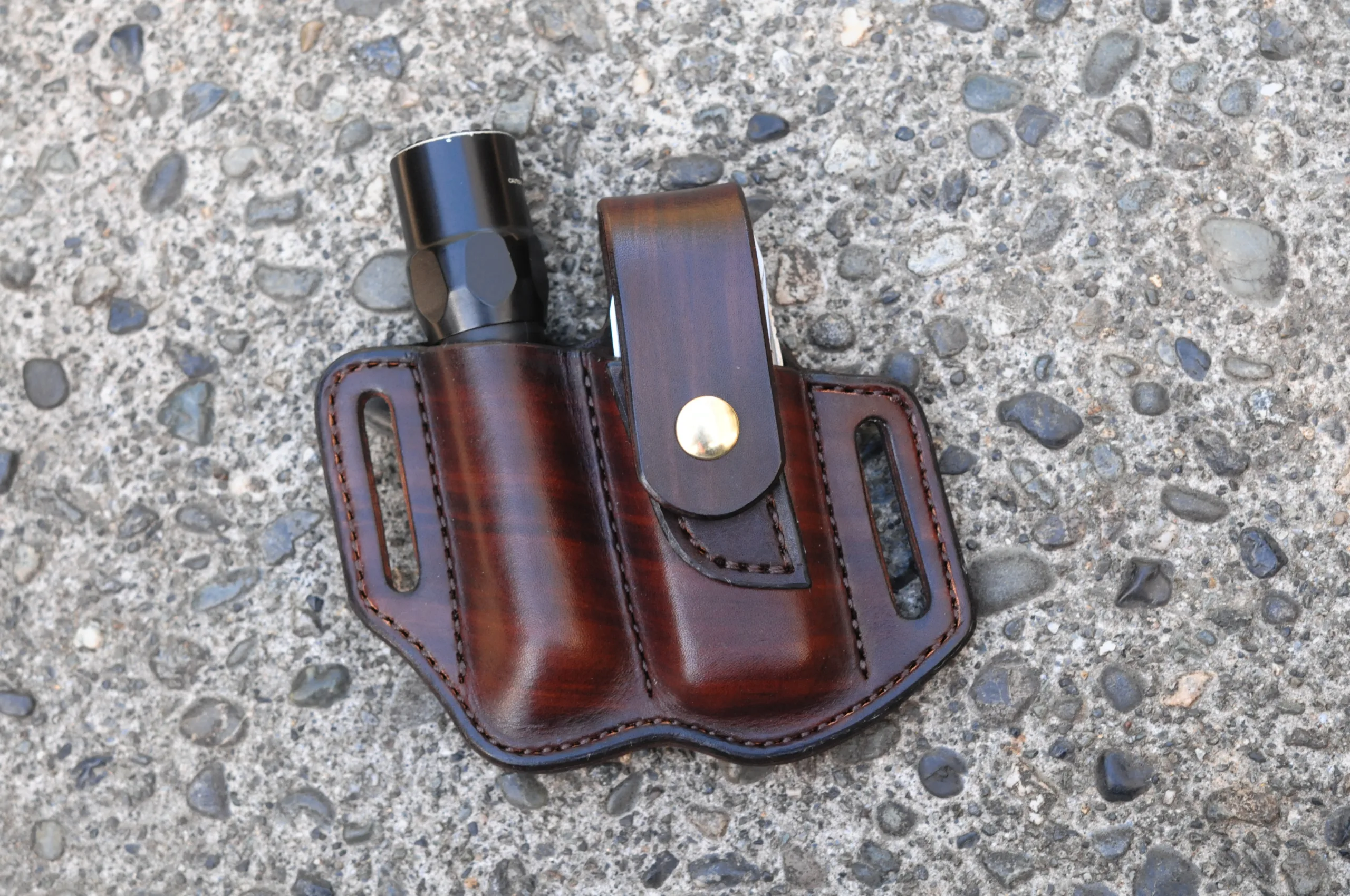 Front view of a belt holster for Leatherman Surge multitool and Surefire flashlight shown in hand dyed chocolate brown leather and configured for left side wearing.