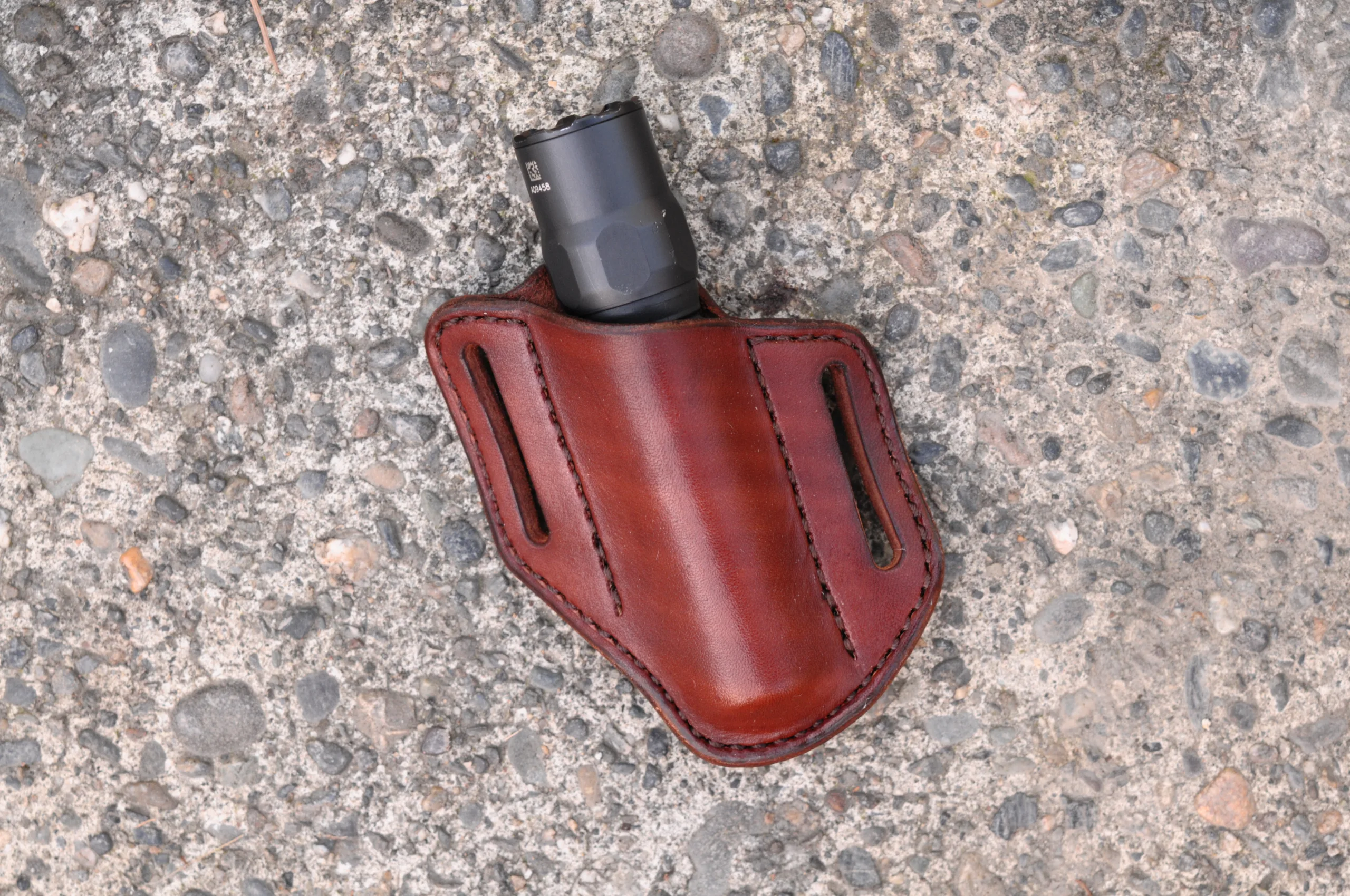 Front view of a leather belt sheath for a 1" tactical flashlight shown in hand dyed mahogany leather