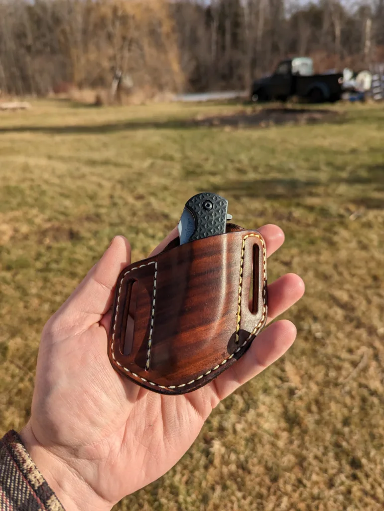 Front view of a belt sheath for a folding knife made from hand dyed brown leather with contrasting white stitching