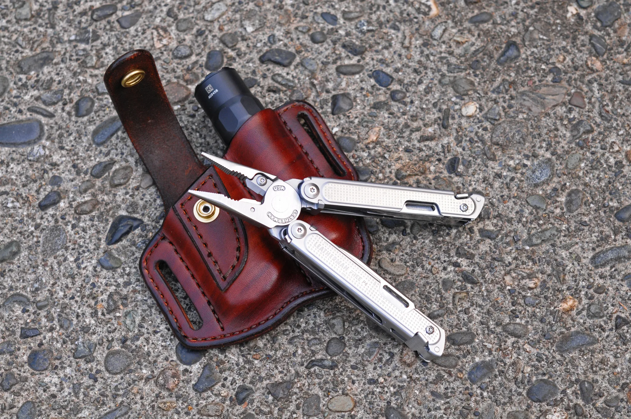 Artistic view of a leather belt sheath for a Leatherman Free P4 multitool and a flashlight