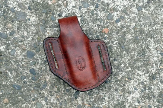 Back view of a Leatherman Surge multitool sheath shown in brown leather with a brass snap