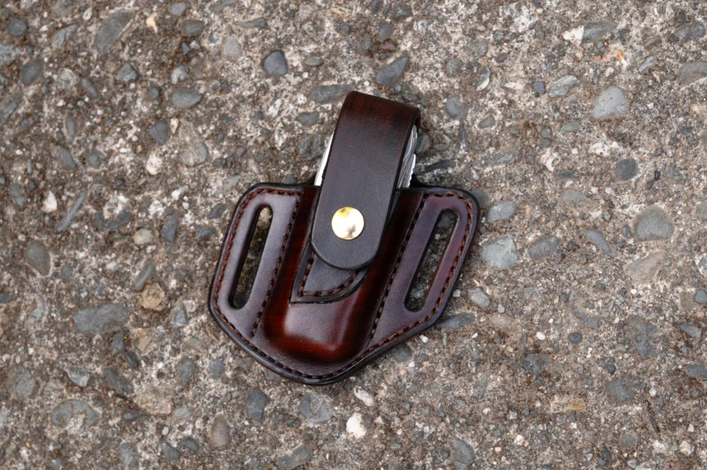 Front view of a Leatherman Surge multitool sheath shown in chocolate brown leather with a brass snap