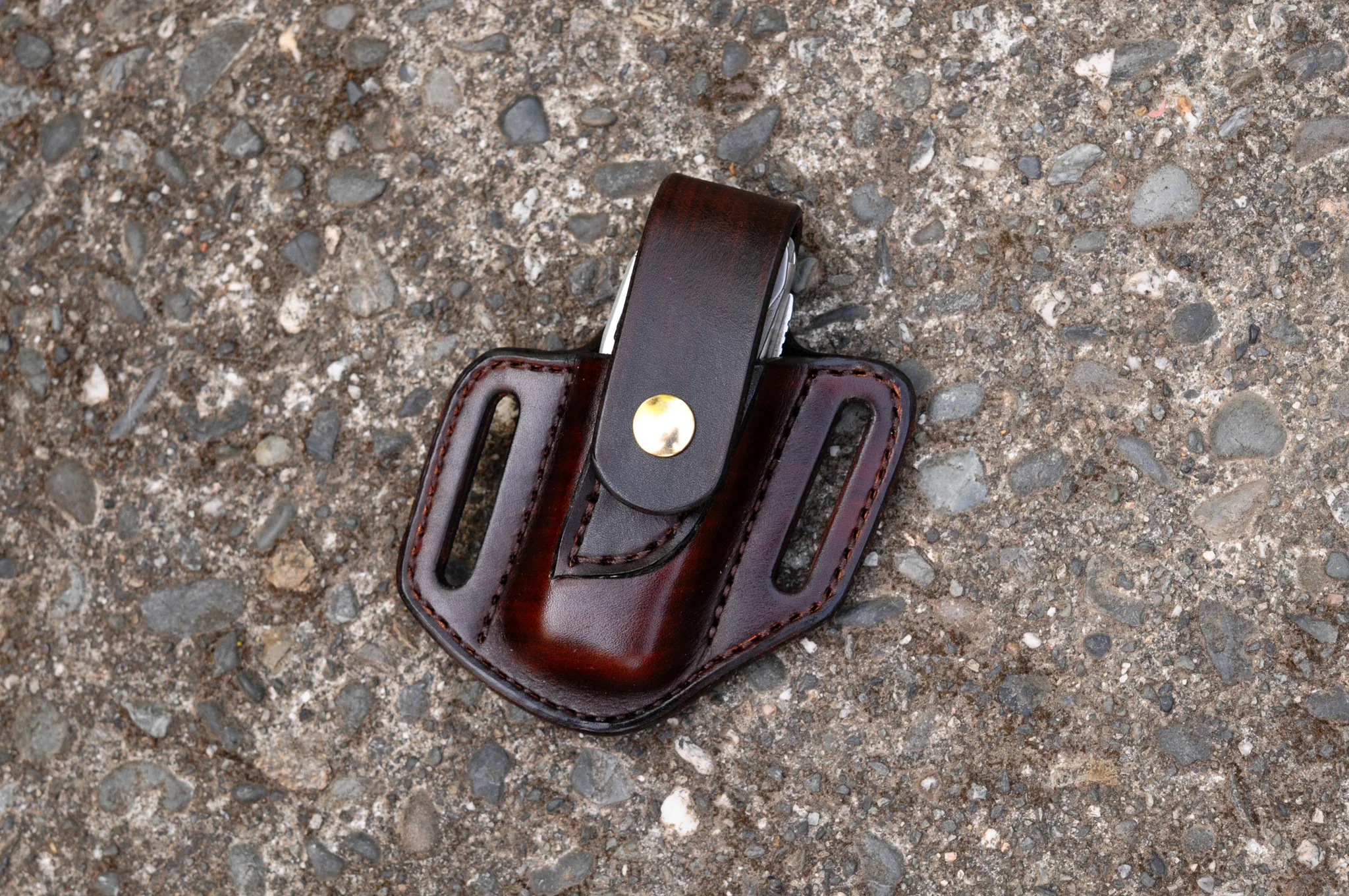 Front view of a Leatherman Surge multitool sheath shown in chocolate brown leather with a brass snap