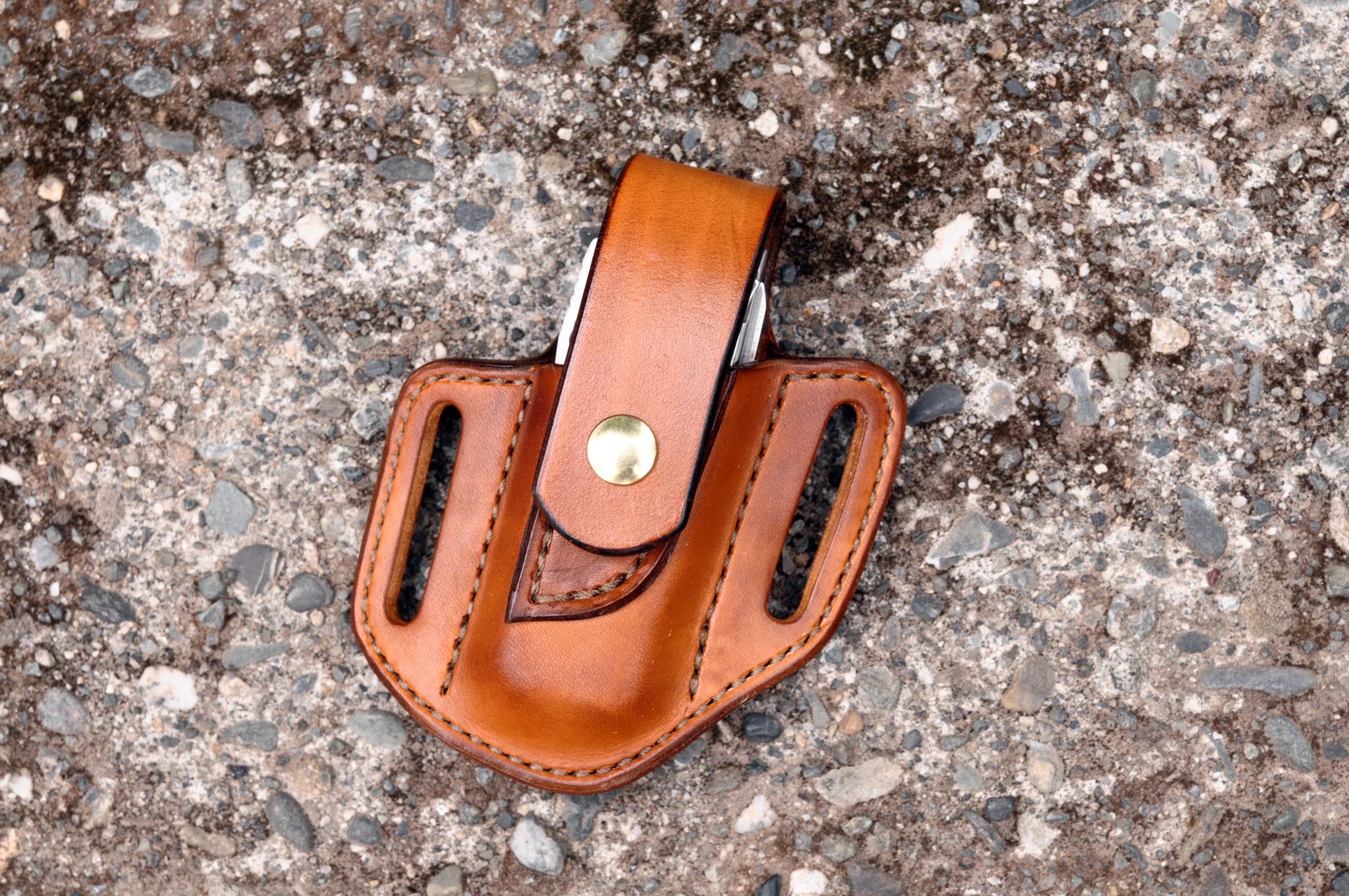 Front view of a Leatherman Surge multitool sheath shown in cognac brown leather with a brass snap
