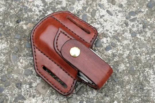 Artistic view of a Leatherman Surge multitool sheath shown in mahogany leather with a brass snap