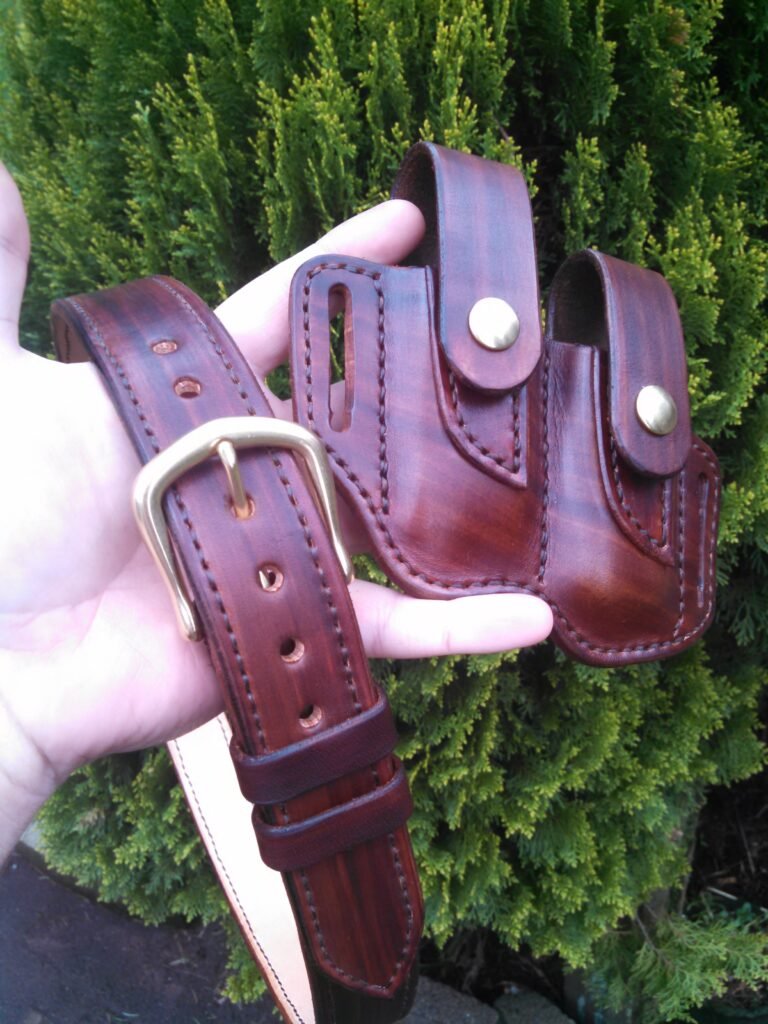 Artistic view of a leather multitool sheath and belt held in front of green vegetation