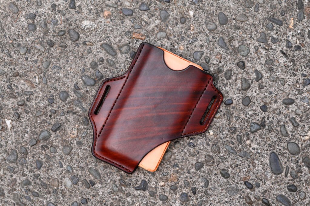 Front view of a leather phone holster. The bottom corner of the phone is exposed for easy pushing up to eject the phone from the holster.