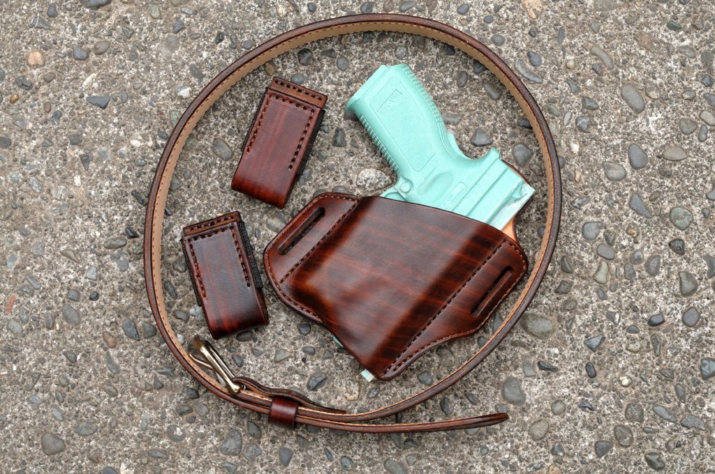 Picture of a hand dyed brown leather holster, magazine pouches and belt set. The holster is for a Springfield XD pistol with a weapon mounted light.