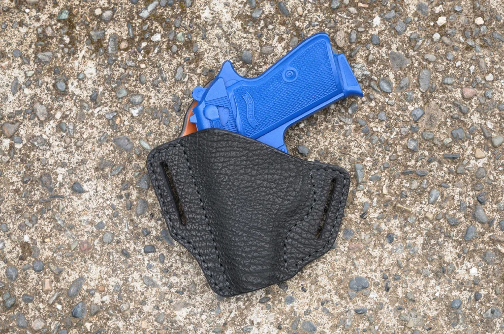 Front view of a black sharkskin holster for a Walther PPK sitting on a cement surface