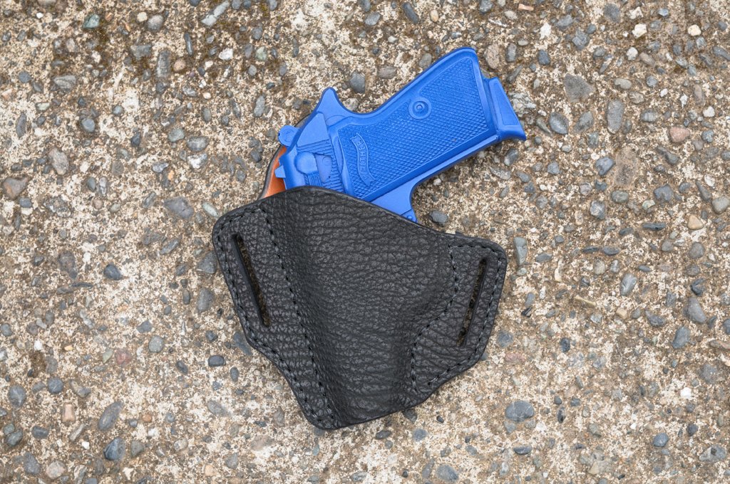 Front view of a black sharkskin holster for a Walther PPK sitting on a cement surface
