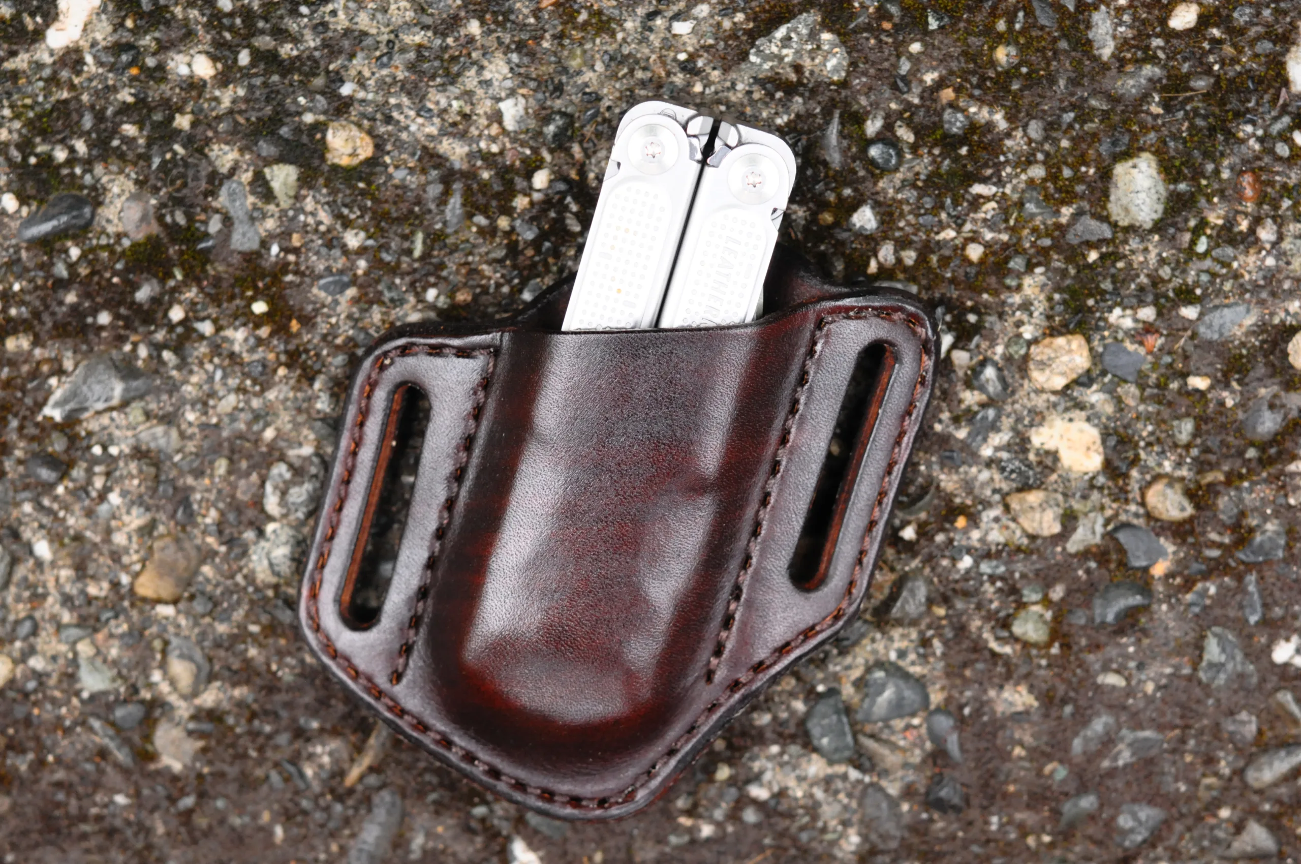 Front view of a chocolate brown open top Leatherman Free P4 sheath sitting on a cement surface